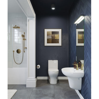 White wall-mount bathroom sink with rounded basin and chrome faucet on dark blue tiled wall.