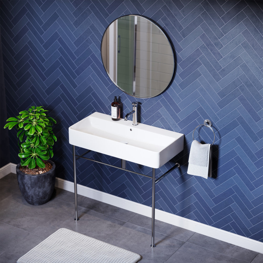 White rectangular ceramic console sink with chrome legs mounted against blue herringbone wall.