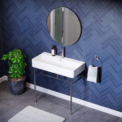 White rectangular ceramic console sink with chrome legs mounted against blue herringbone wall.