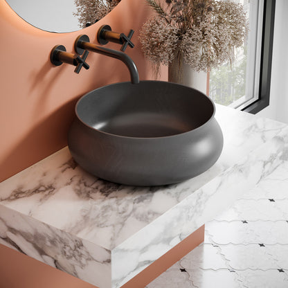 17.5" round concrete vessel bathroom sink in dark gray with matte finish and wall-mounted faucet.