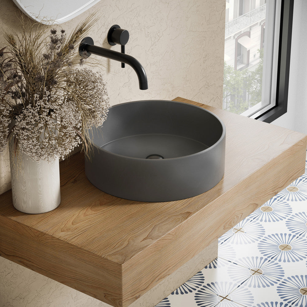 14.5" round concrete vessel bathroom sink in dark gray with matte black wall-mounted faucet.
