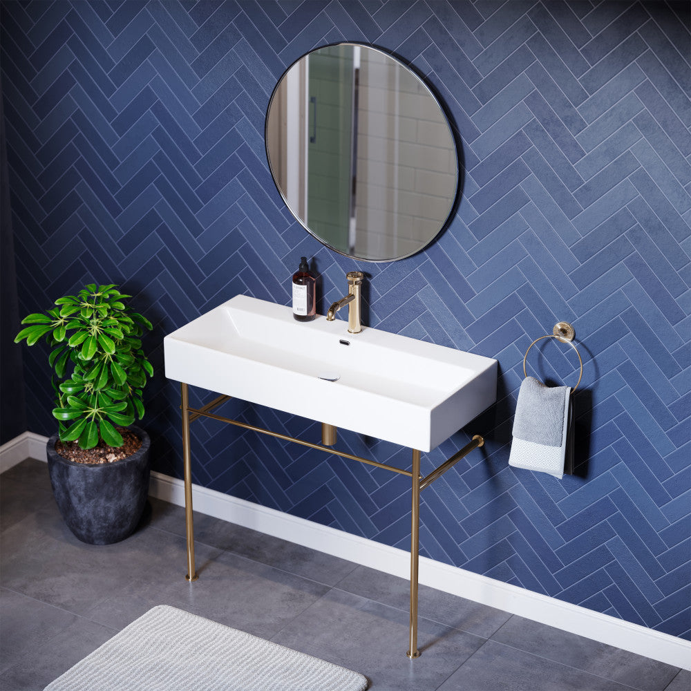 Rectangular white ceramic console sink with slim gold metal legs and single faucet hole.