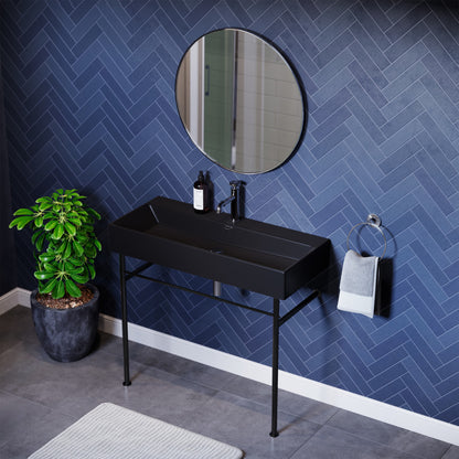 Matte black ceramic console sink with black metal legs and round wall mirror, modern bathroom design.