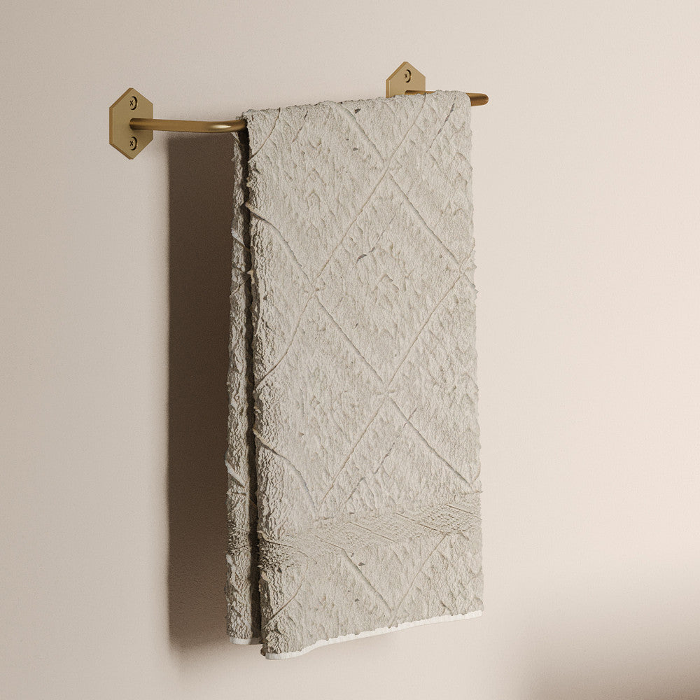 12" towel bar in brushed gold with geometric wall mounts and textured beige towel hanging.