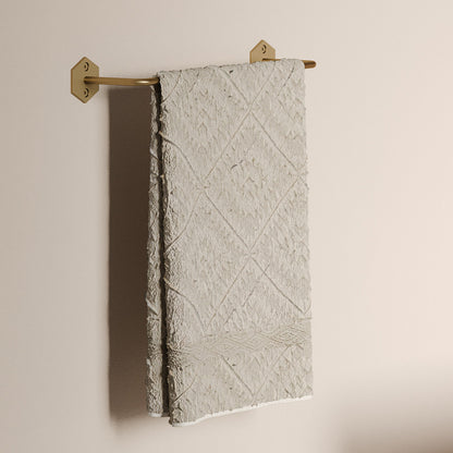 12" towel bar in brushed gold with geometric wall mounts and textured beige towel hanging.