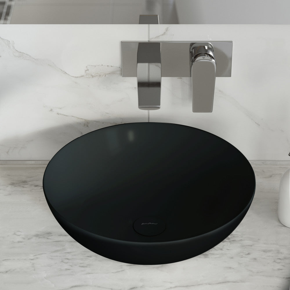 Round vessel sink in matte black ceramic with minimalist wall-mounted faucet and handle.