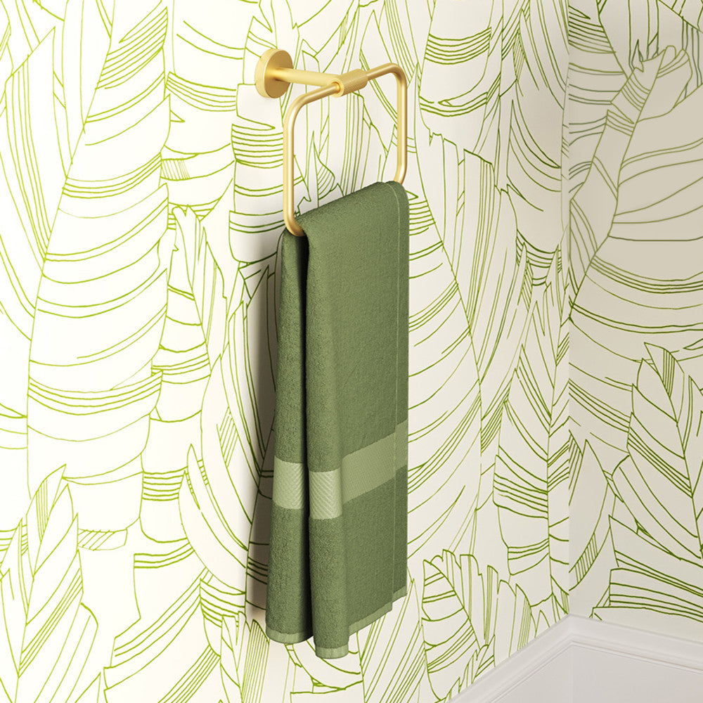 Avallon towel ring in brushed gold finish holding a folded green towel with a striped pattern.
