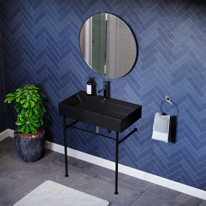 Matte black rectangular ceramic console sink with black metal legs and round mirror above.